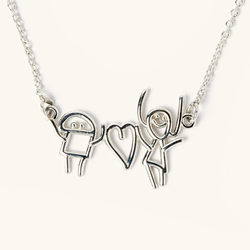Custom silver necklace featuring two child-like drawing characters holding a heart, transformed into a pendant on a chain.