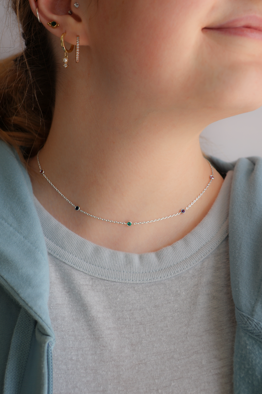 Close-up of a person wearing a birthstone necklace with small gemstones