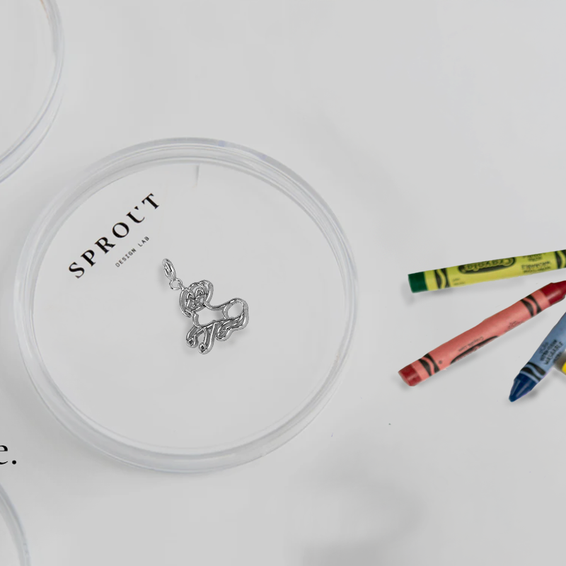 Custom silver dog charm displayed in a clear dish with crayons in the background