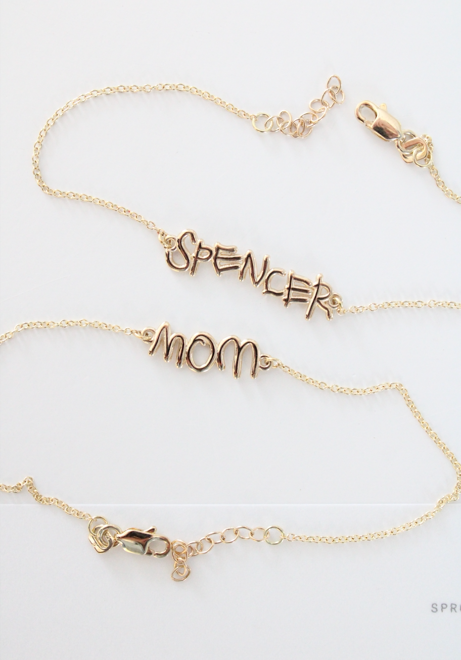 Custom gold handwriting bracelets by Sprout featuring “Spencer” and “mom,” personalized from real handwriting into meaningful jewelry