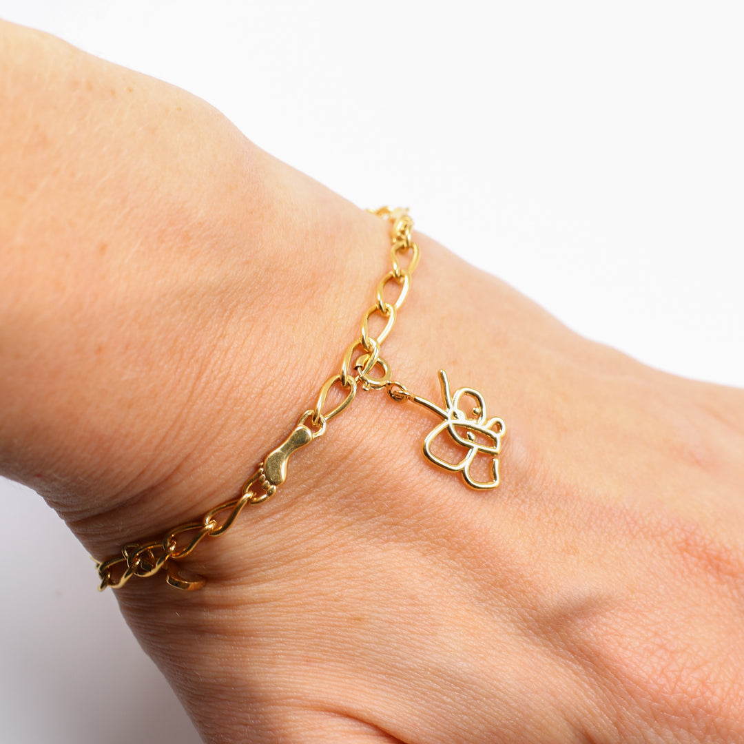 Gold bracelet with butterfly charm on wrist against a white background