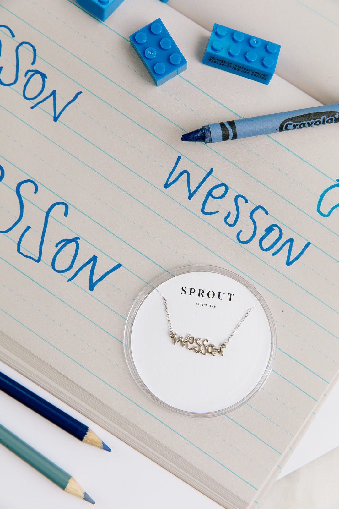 Custom handwriting necklace spelling “Wesson” displayed with handwritten name in blue crayon.