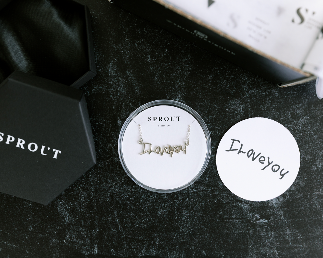 Custom handwriting necklace spelling “I love you” displayed in Sprout packaging with handwritten card.